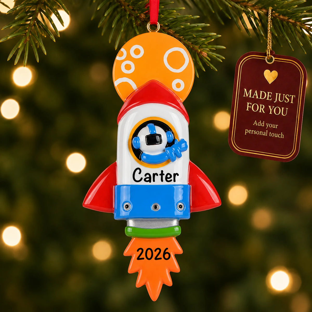 Space rocket christmas ornament hanging on a lit Christmas tree with a Made Just For You gift tag
