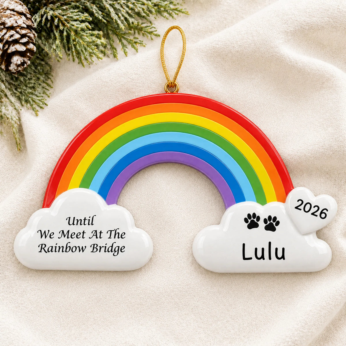 Personalized Pet Rainbow Bridge Memorial christmas ornament laid on a soft white knit blanket