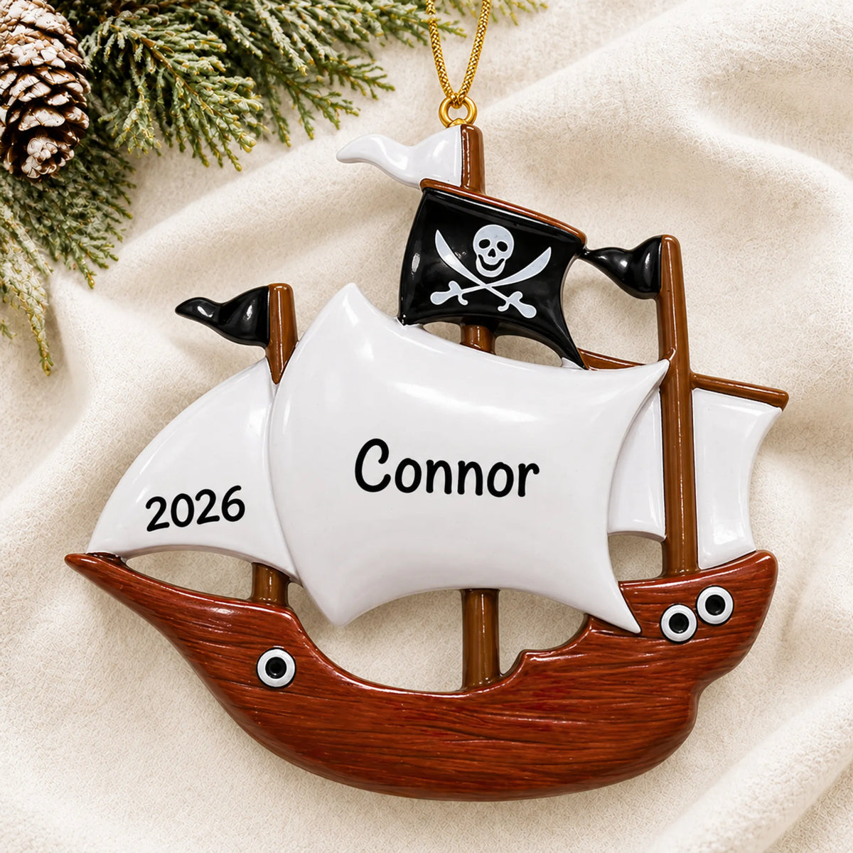 Personalized pirate ship kids christmas ornament laid on a soft white knit blanket