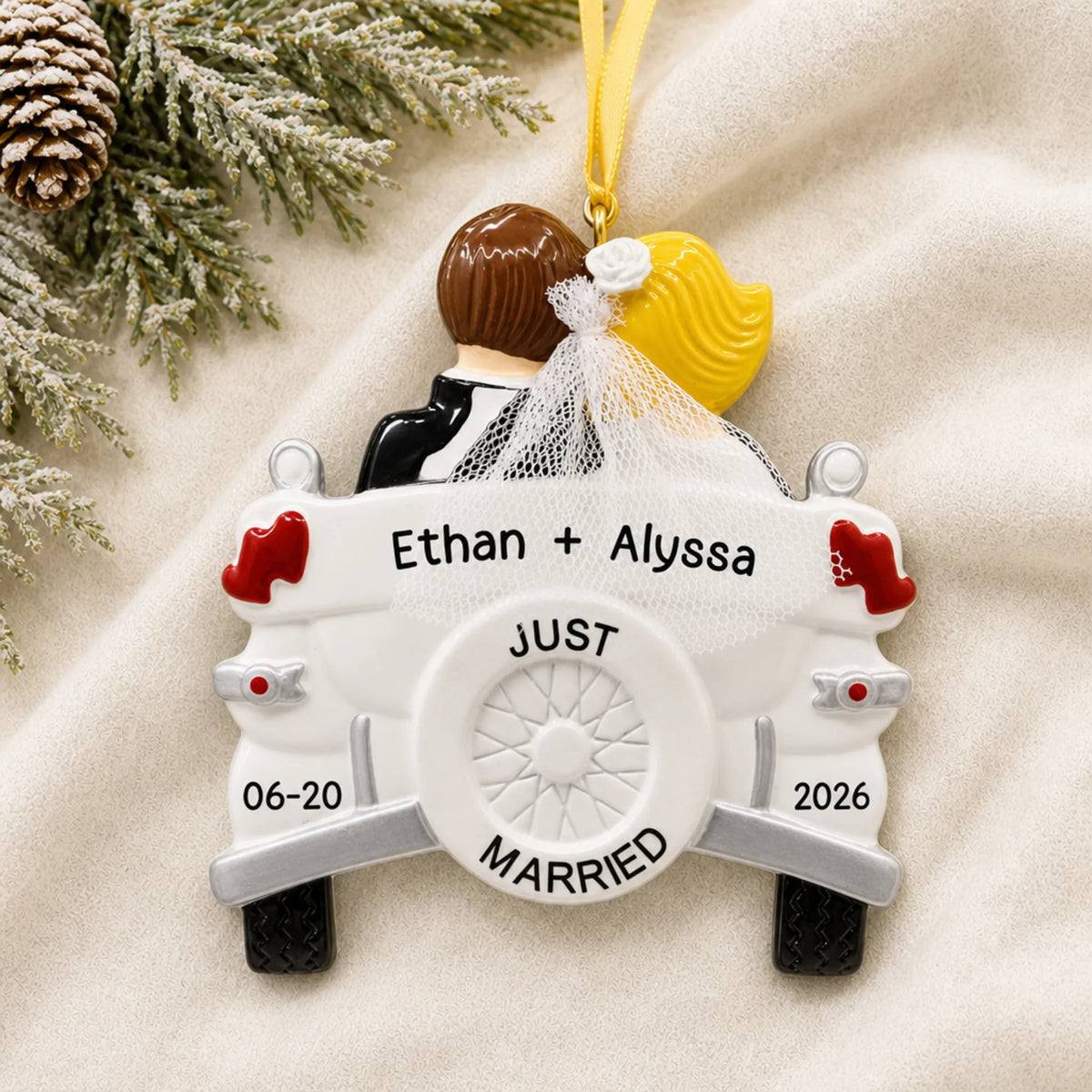 Personalized blonde Just Married wedding car Christmas ornament on a cream knit blanket beside pine and pinecones