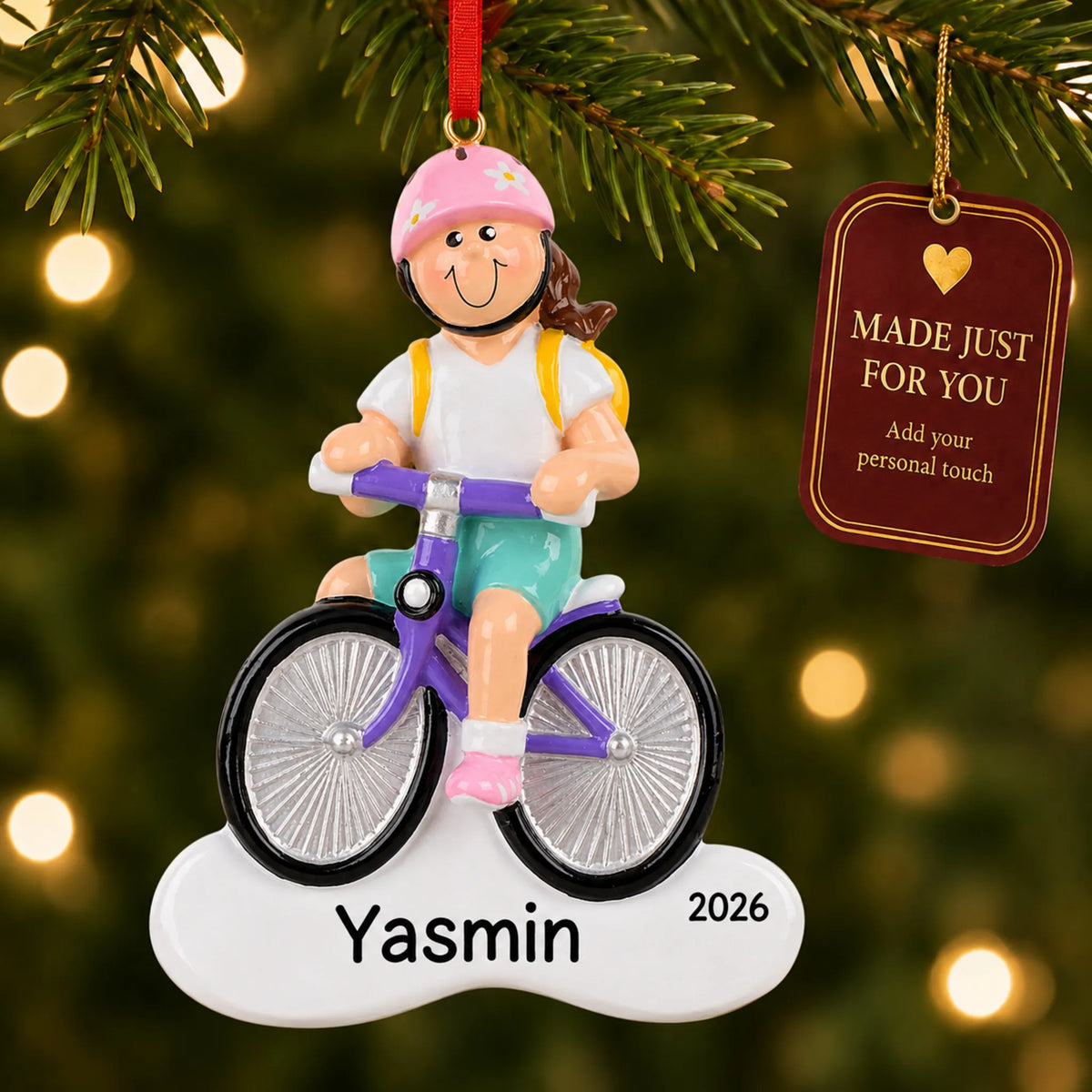 Brunette girl bike christmas ornament hanging on a lit Christmas tree with a Made Just For You gift tag