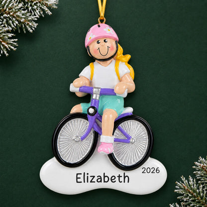 Personalized blonde girl bike christmas ornament on a dark green pine background