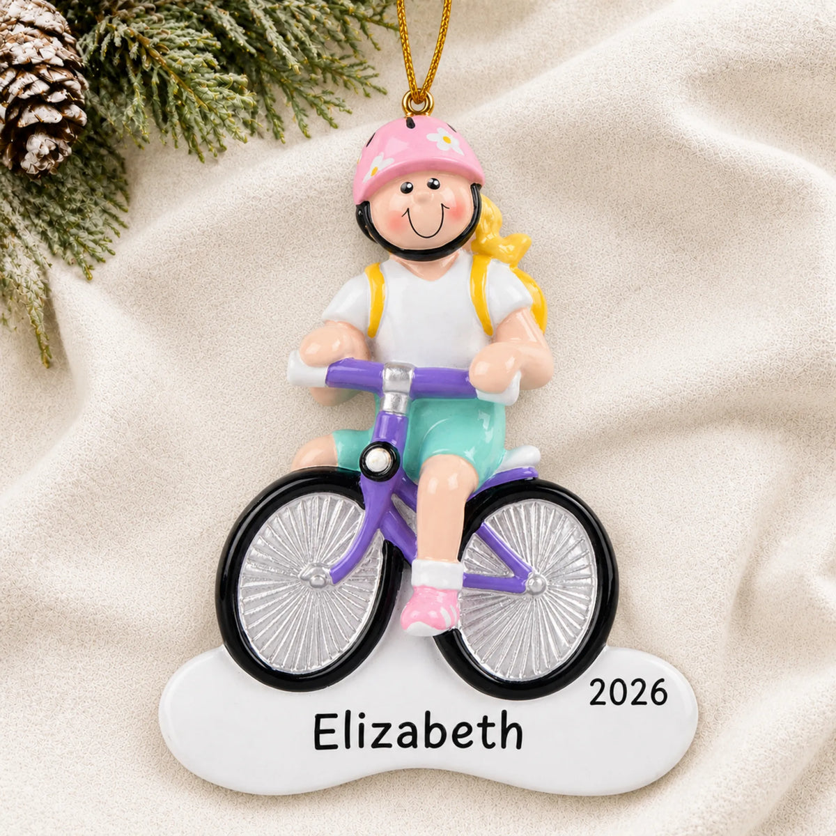 Personalized blonde girl bike christmas ornament laid on a soft white knit blanket