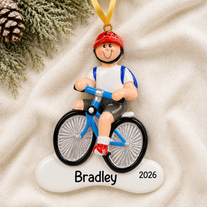 Personalized boy riding a bike christmas ornament laid on a soft white knit blanket
