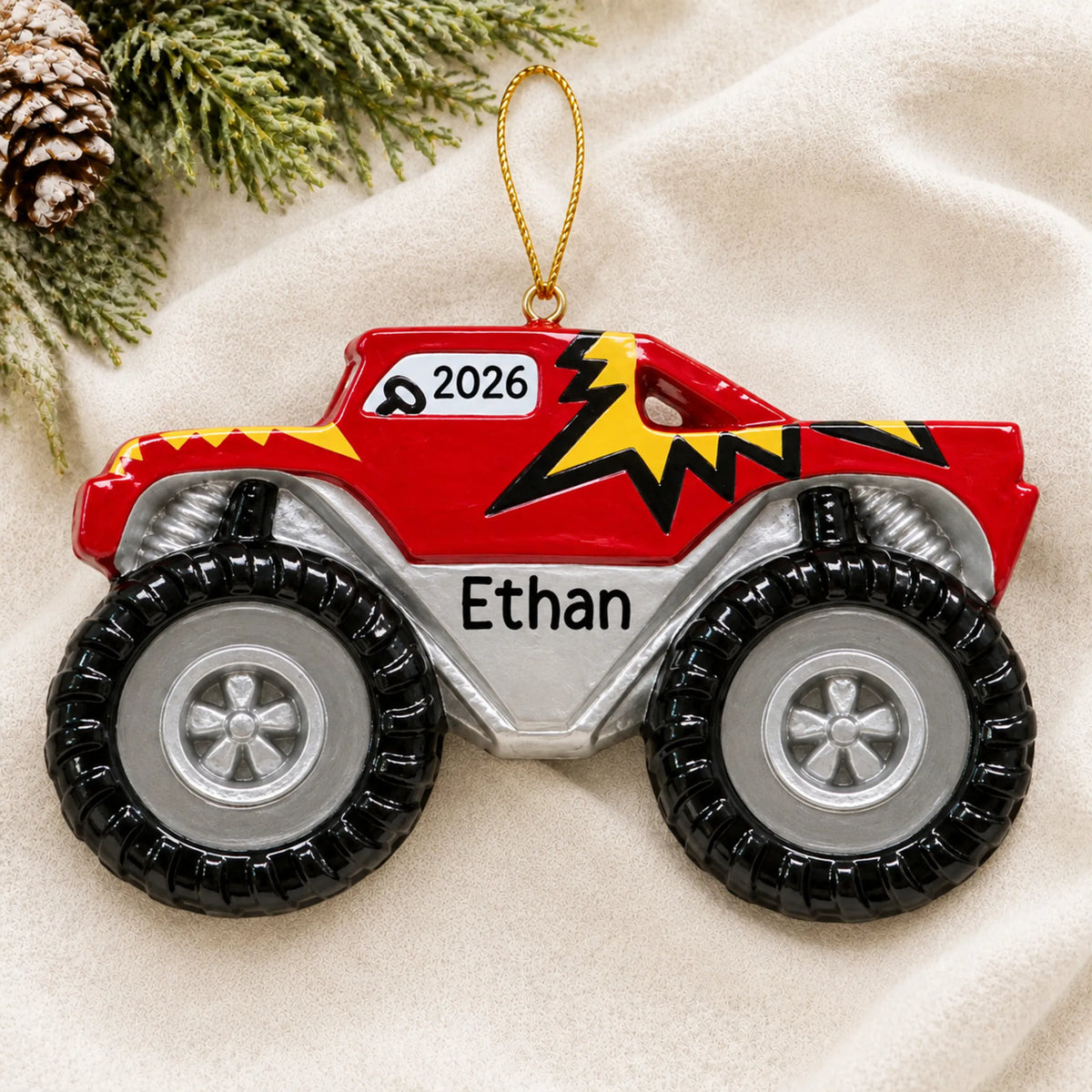 Personalized monster truck big wheels christmas ornament laid on a soft white knit blanket