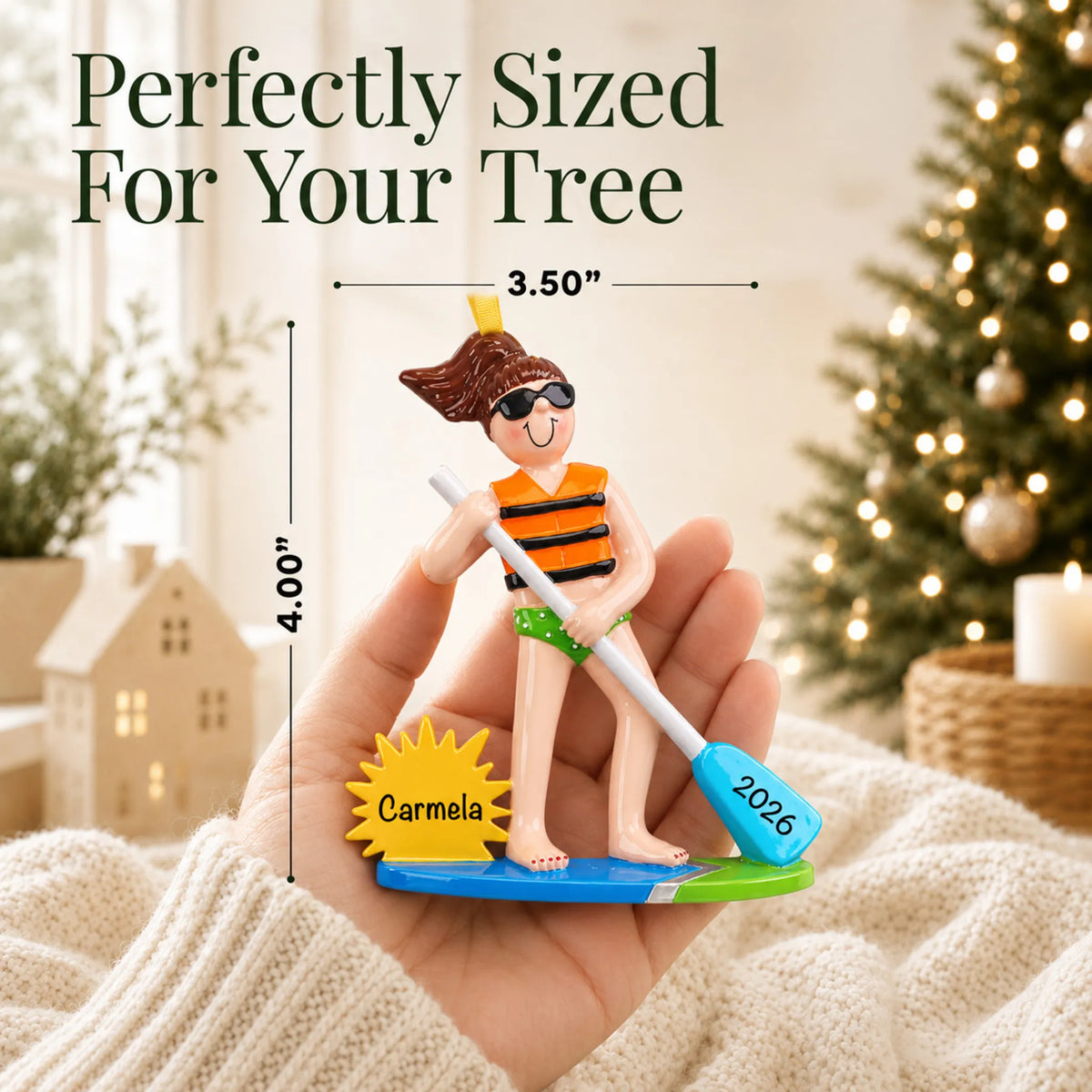 Size guide: the personalized paddle board girl christmas ornament shown in hand next to a Christmas tree