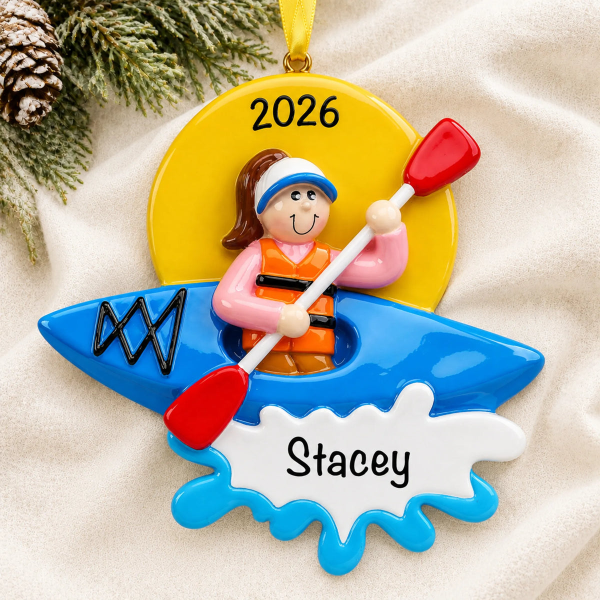 Personalized kayak girl christmas ornament laid on a soft white knit blanket