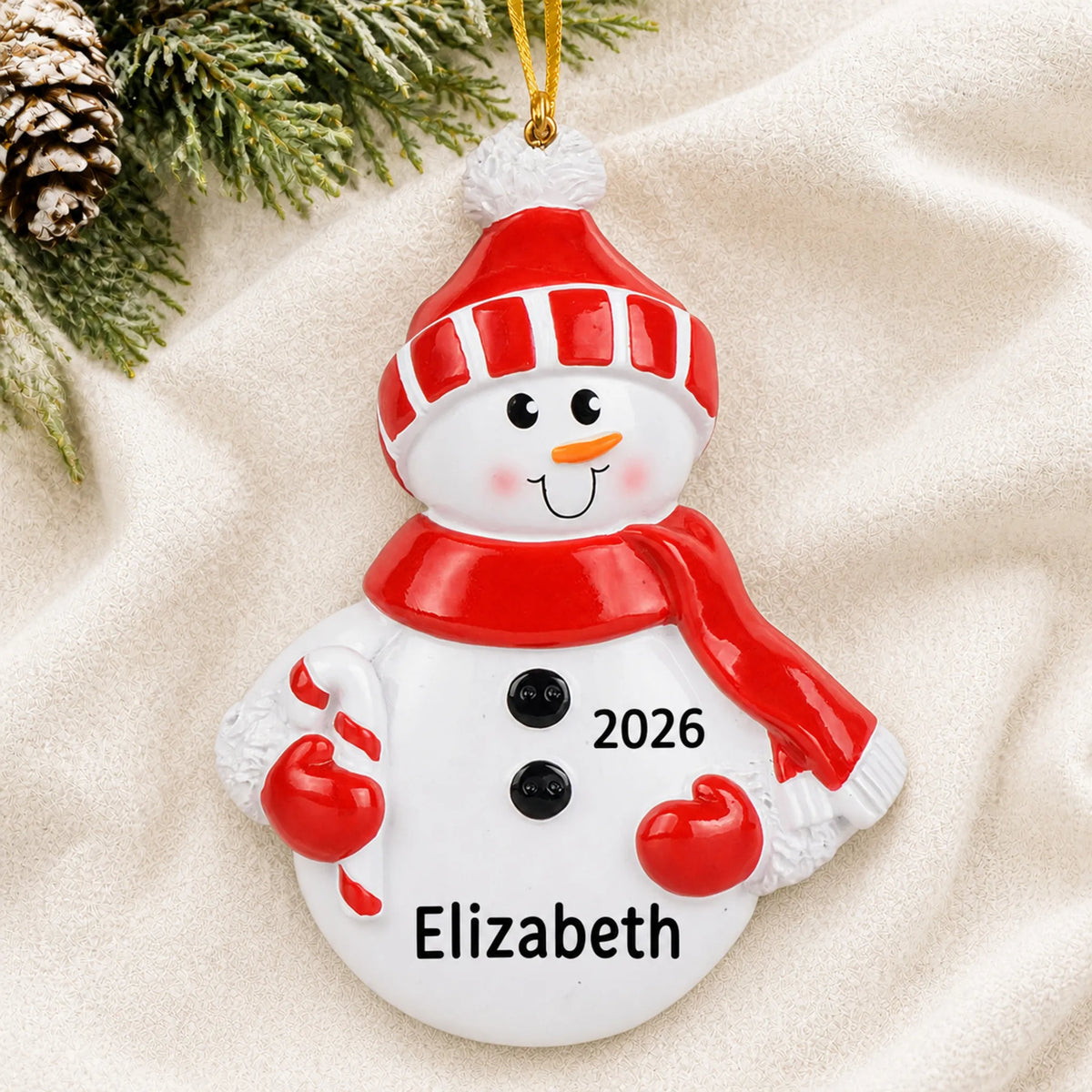 Personalized Snowman Red Hat christmas ornament laid on a soft white knit blanket