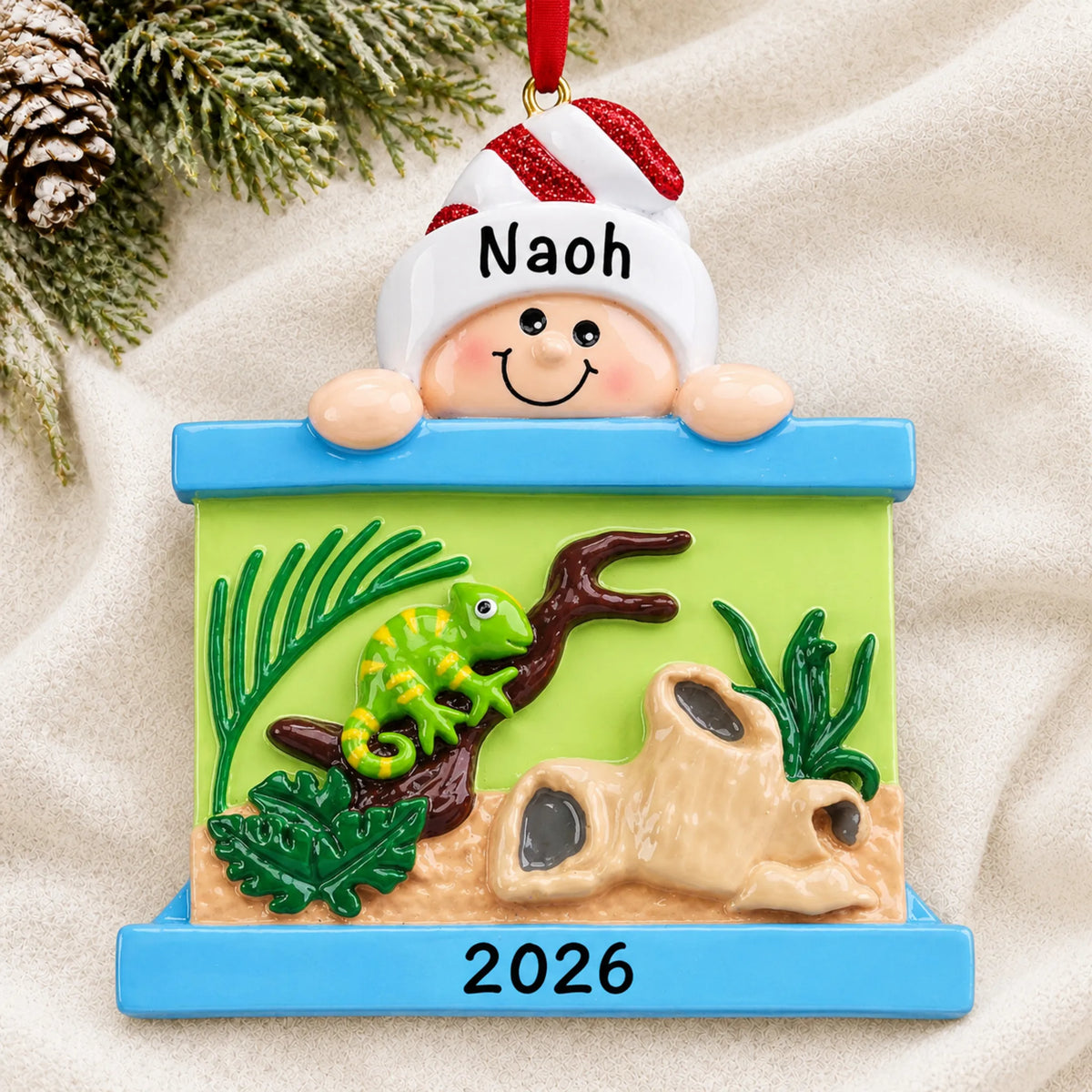 Personalized Reptile Lover christmas ornament laid on a soft white knit blanket