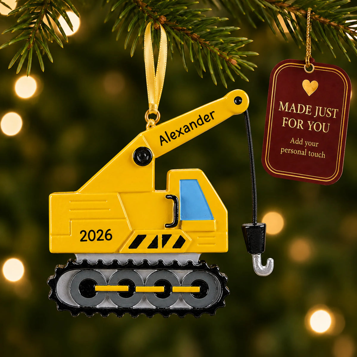 Construction crane christmas ornament hanging on a lit Christmas tree with a Made Just For You gift tag