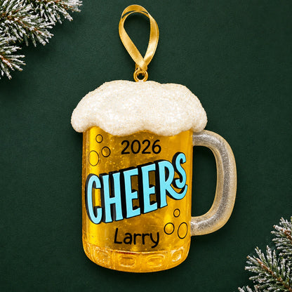 Personalized beer mug Christmas ornament reading Cheers, Larry, and 2026, shown on a dark green background with pine