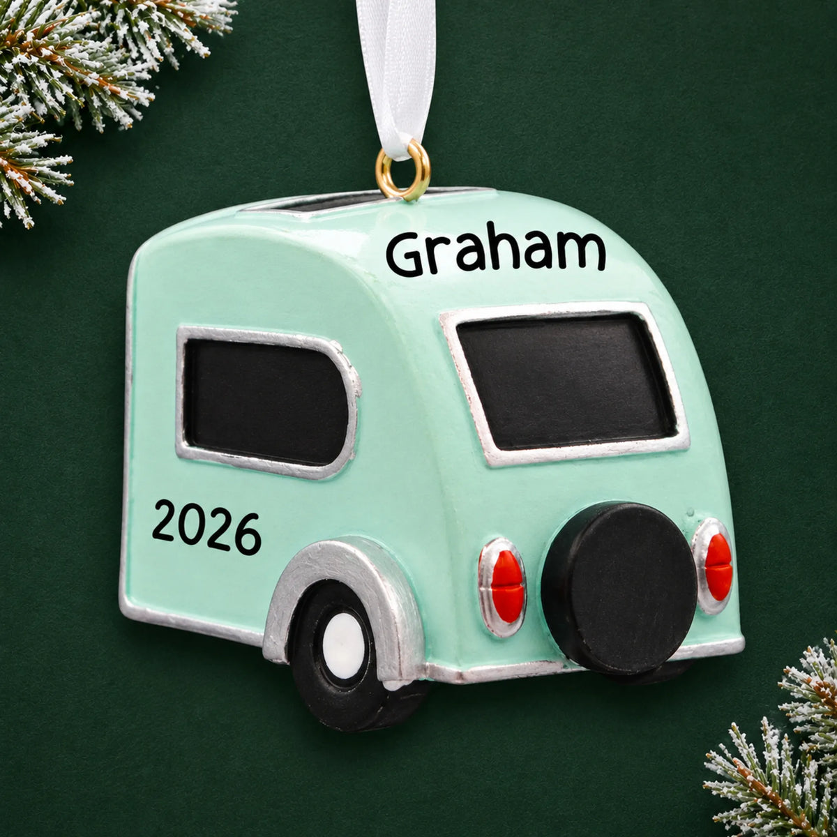 Personalized teardrop camper trailer christmas ornament on a dark green pine background