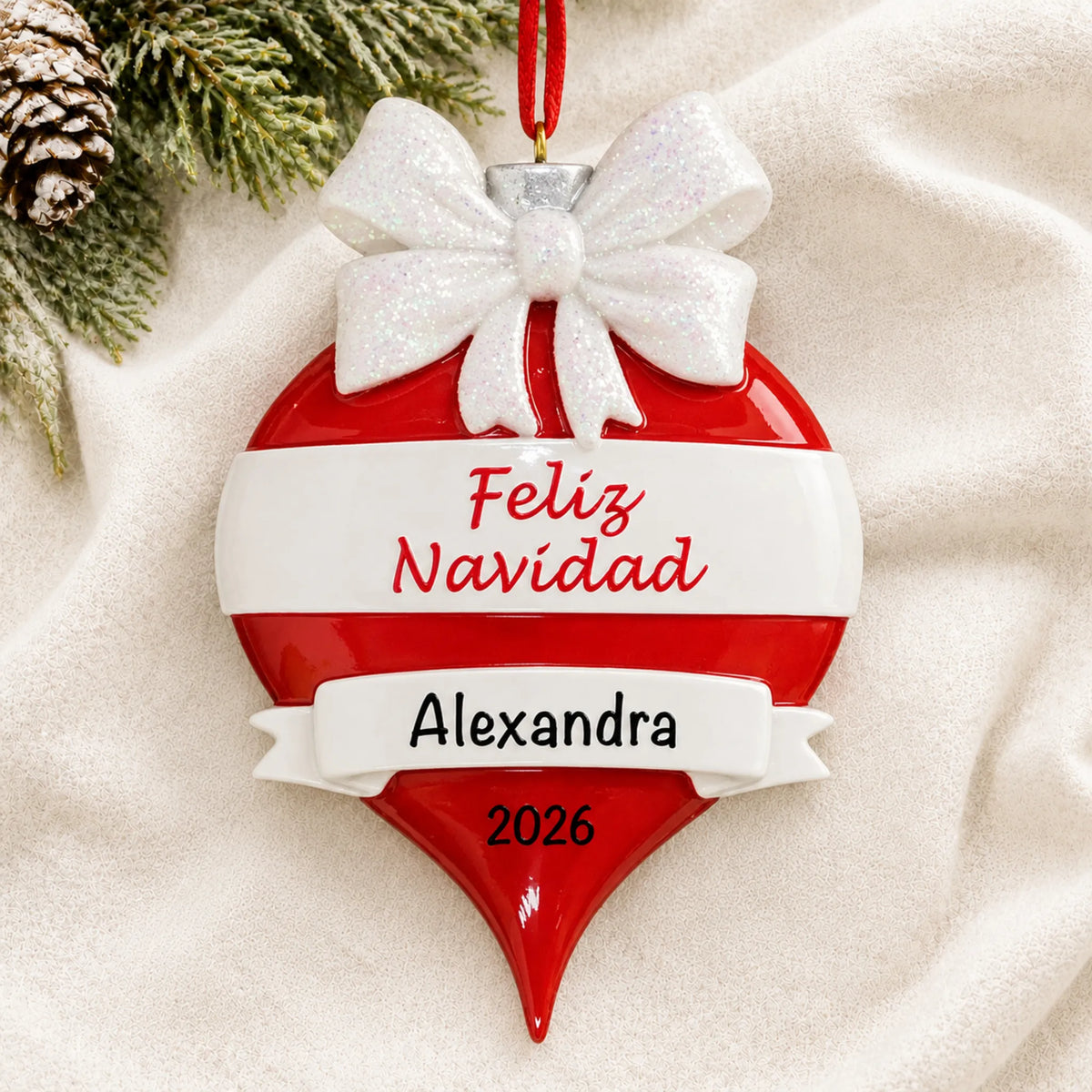 Personalized Feliz Navidad christmas ornament laid on a soft white knit blanket