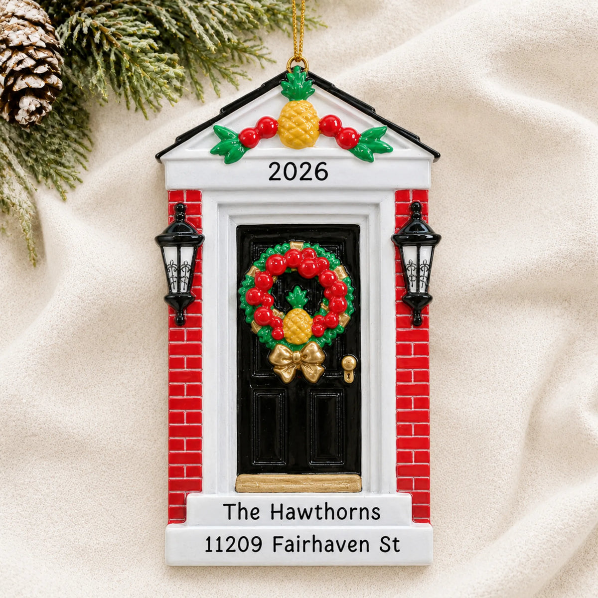 Personalized Red Brick Home Door christmas ornament laid on a soft white knit blanket