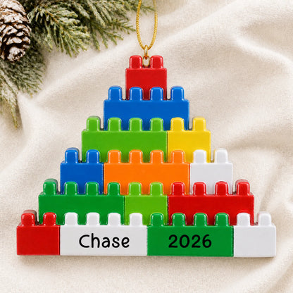 Personalized building blocks christmas ornament laid on a soft white knit blanket