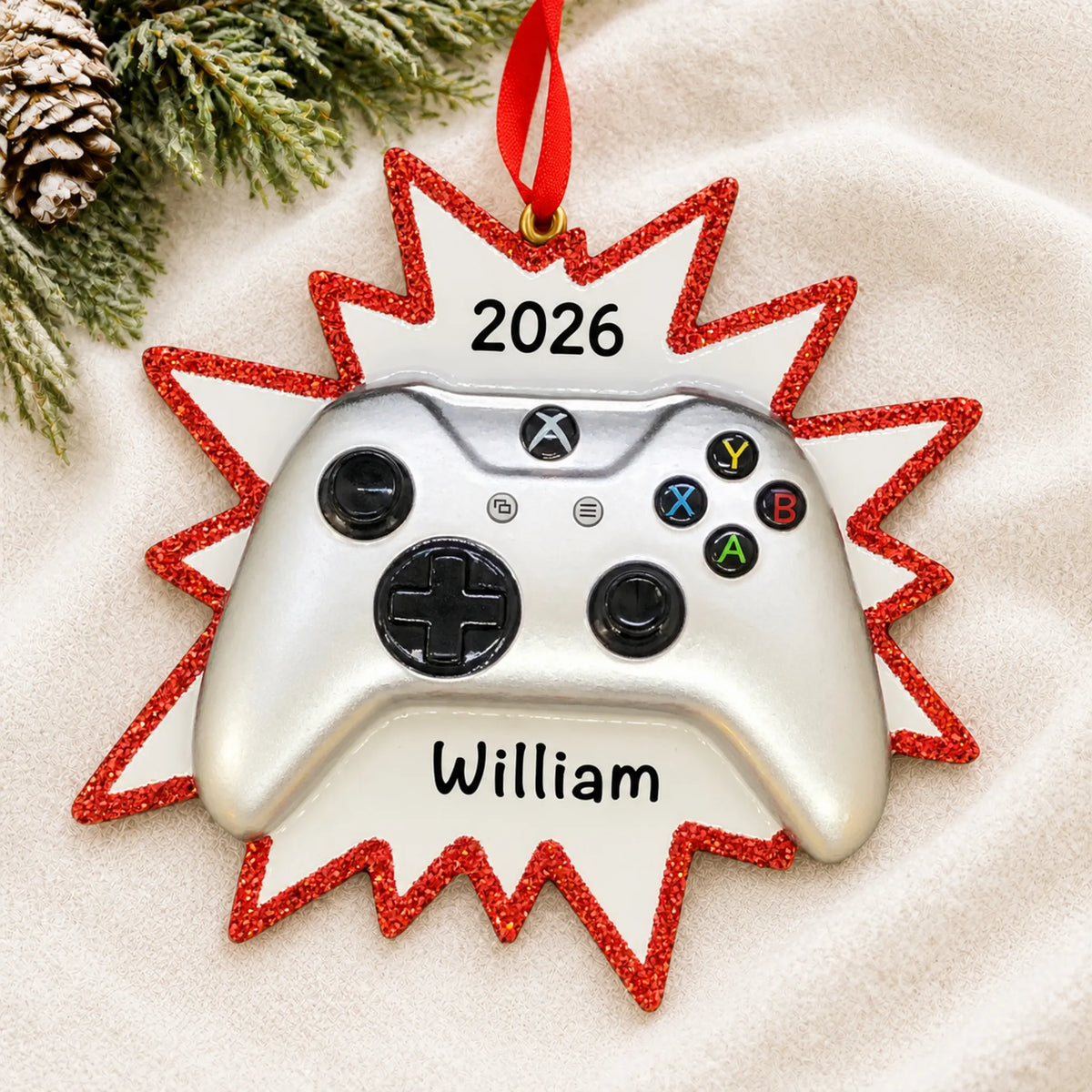 Personalized silver video game controller christmas ornament laid on a soft white knit blanket