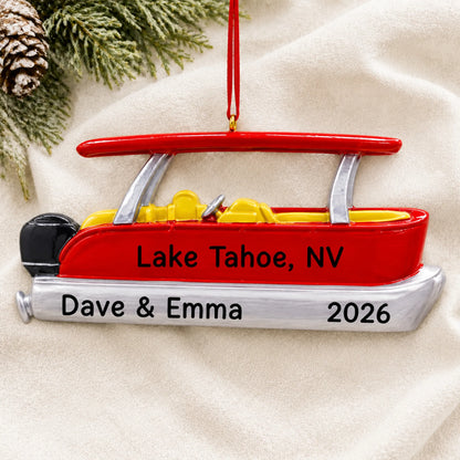 Personalized red pontoon boat christmas ornament laid on a soft white knit blanket