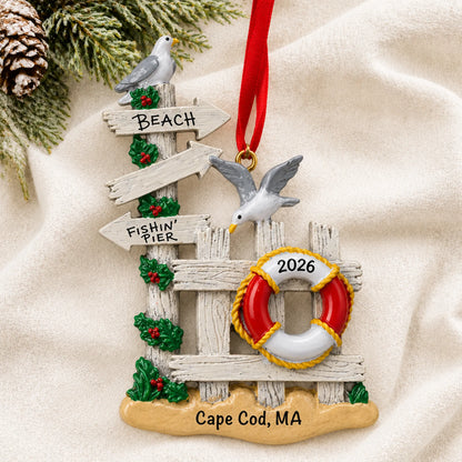 Personalized beach gate christmas ornament laid on a soft white knit blanket