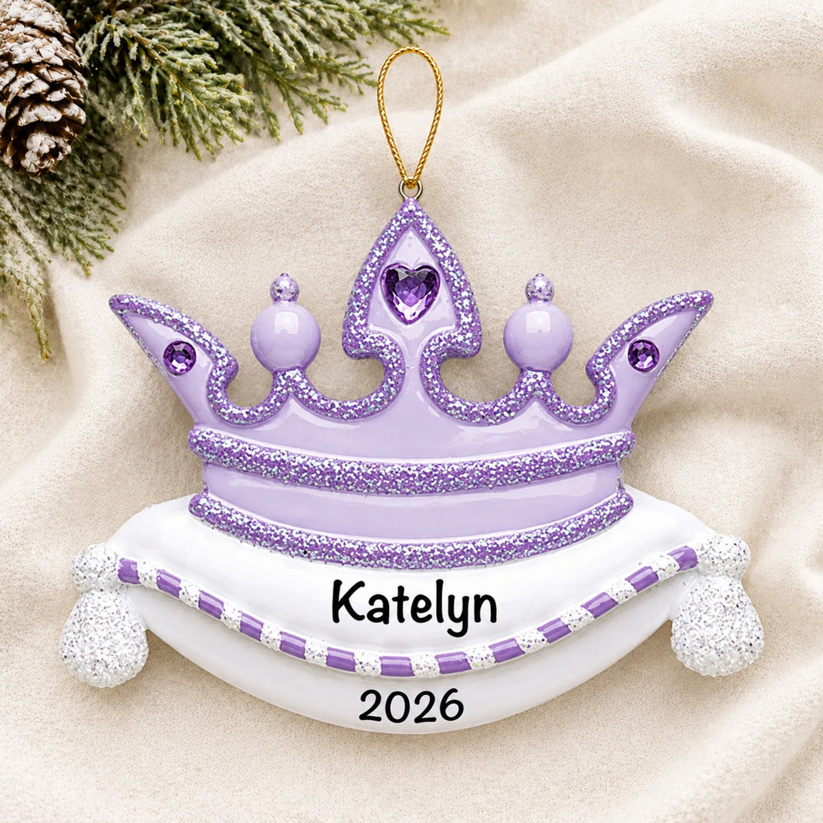 Personalized purple princess crown christmas ornament laid on a soft white knit blanket