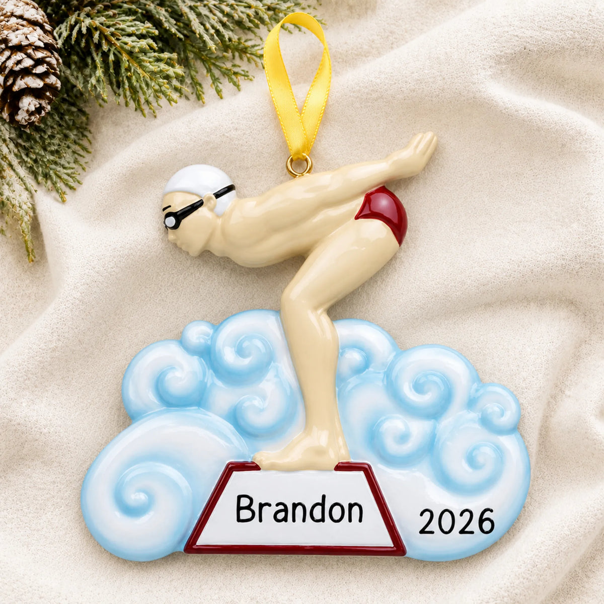 Personalized boy swimmer christmas ornament laid on a soft white knit blanket