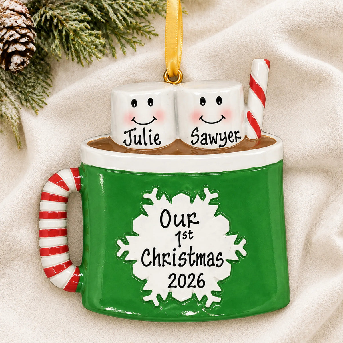 Personalized hot cocoa couple christmas ornament laid on a soft white knit blanket