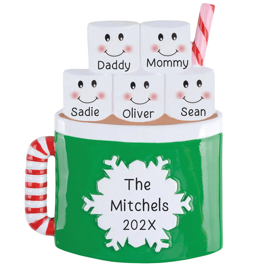 A personalized holiday ornament designed like a mug with 'The Mitchels Year' text and five small figures with names. It has a green color scheme with a candy cane handle and is engraved with smiling faces.