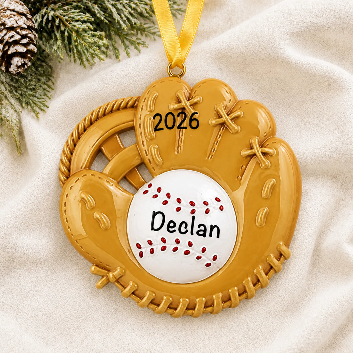 Personalized baseball catcher's mitt christmas ornament laid on a soft white knit blanket