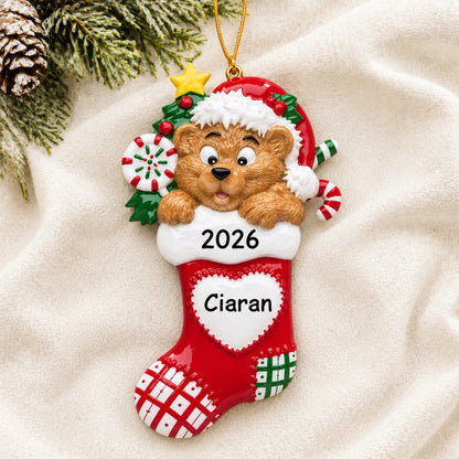 Personalized Bear Stocking christmas ornament laid on a soft white knit blanket