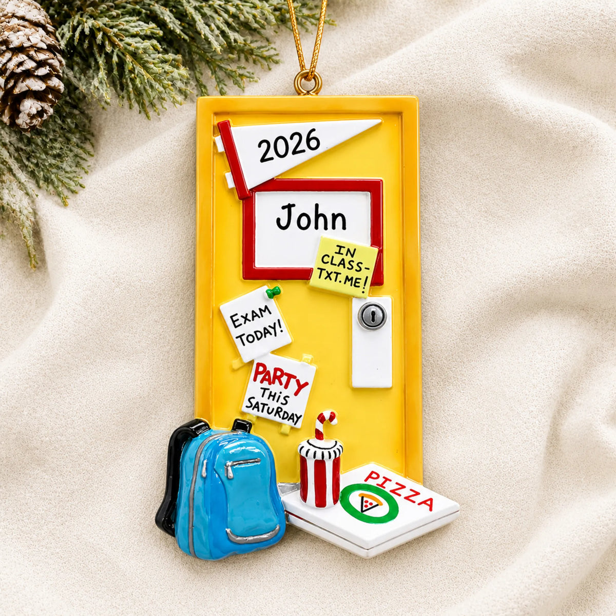Personalized college student dorm room christmas ornament laid on a soft white knit blanket