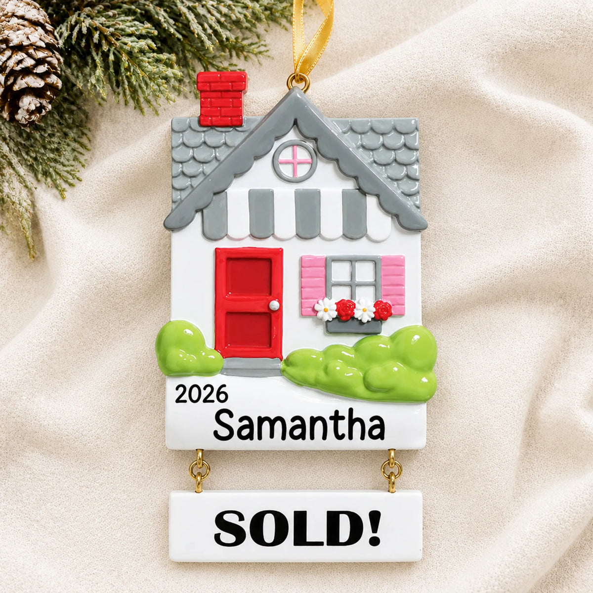 Personalized Real Estate Sold House christmas ornament laid on a soft white knit blanket