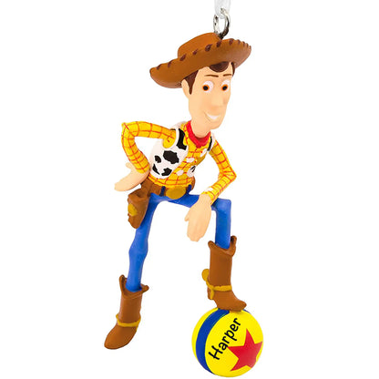 Personalized Christmas ornament featuring Sheriff Woody from Disney/Pixar Toy Story in his cowboy outfit, standing on the Pixar Ball, with the ball ready for custom name engraving.