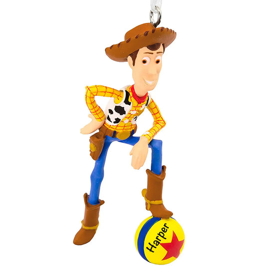 Personalized Christmas ornament featuring Sheriff Woody from Disney/Pixar Toy Story in his cowboy outfit, standing on the Pixar Ball, with the ball ready for custom name engraving.