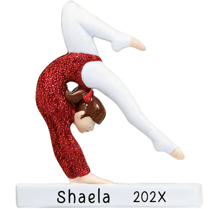 A personalized gymnastics ornament featuring a glittery red outfit gymnast in a balancing pose with 'SHAELA YEAR' text below.
