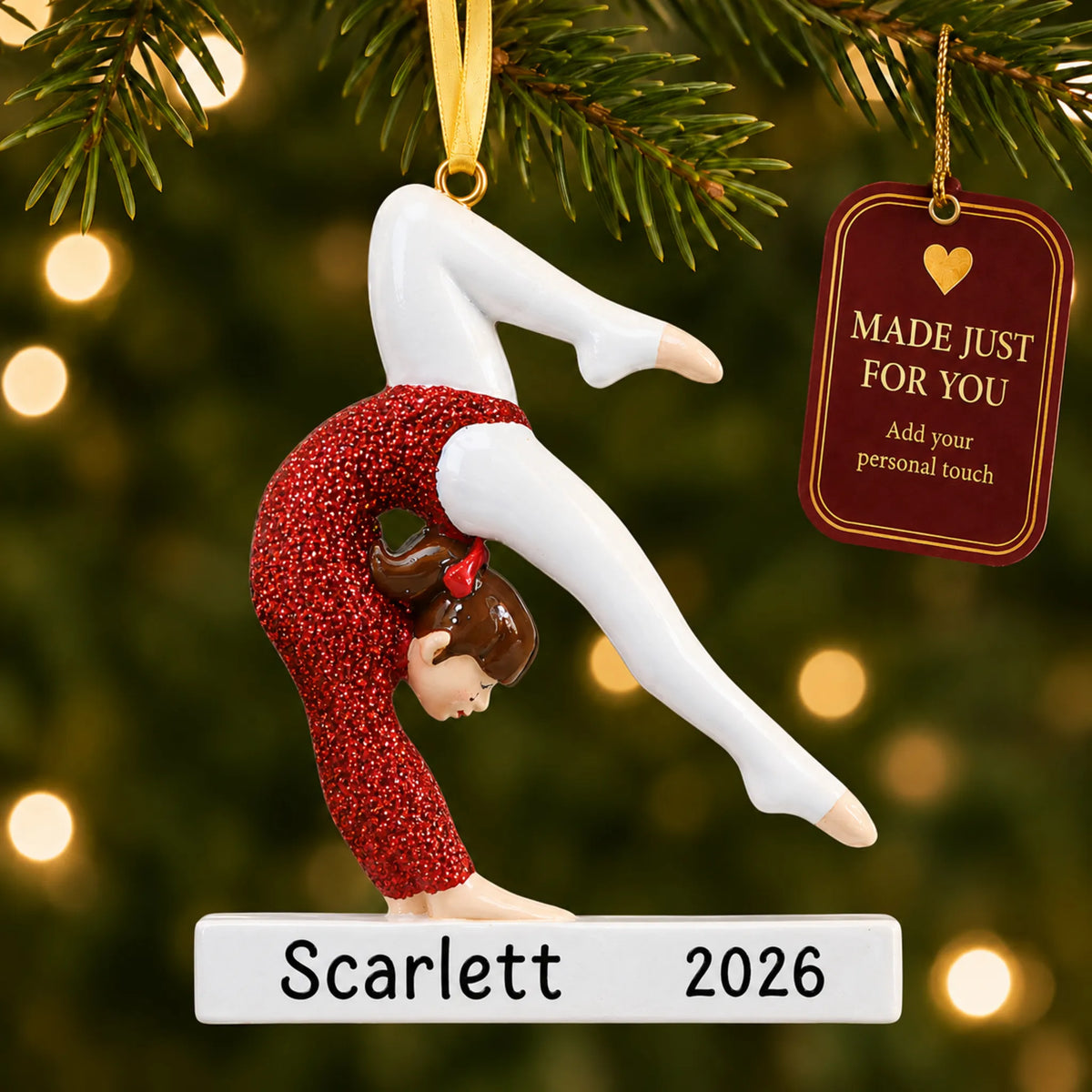 Red glitter gymnastics girl christmas ornament hanging on a lit Christmas tree with a Made Just For You gift tag