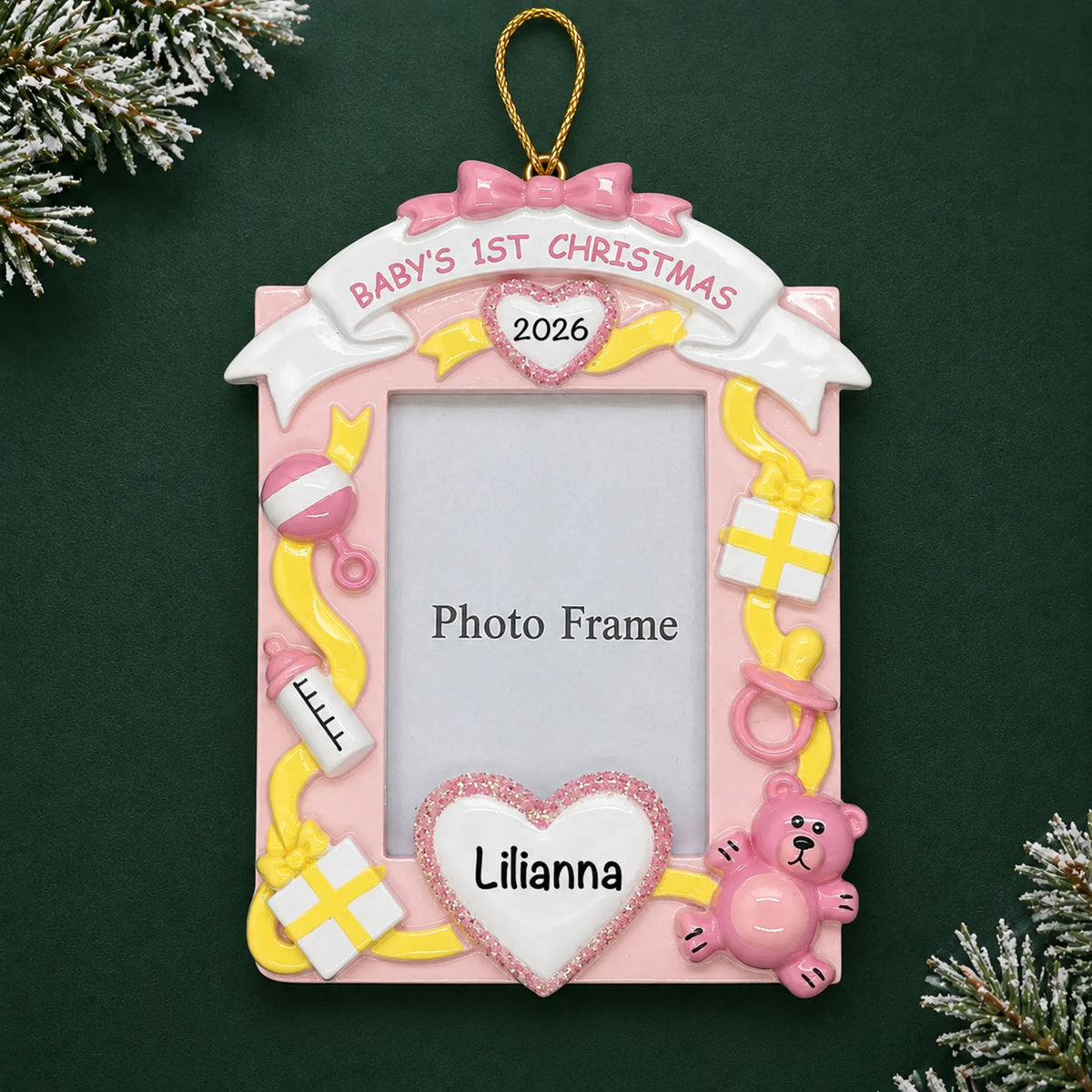 Personalized pink baby's 1st christmas photo frame ornament on a dark green pine background
