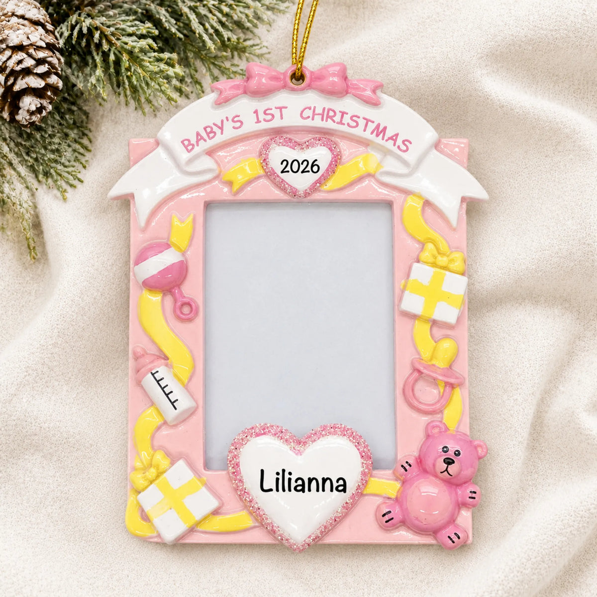 Personalized pink baby's 1st christmas photo frame ornament laid on a soft white knit blanket