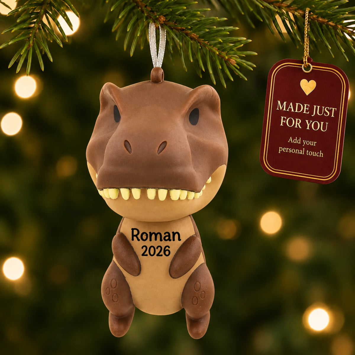 Brown t-rex dinosaur christmas ornament hanging on a lit Christmas tree with a Made Just For You gift tag