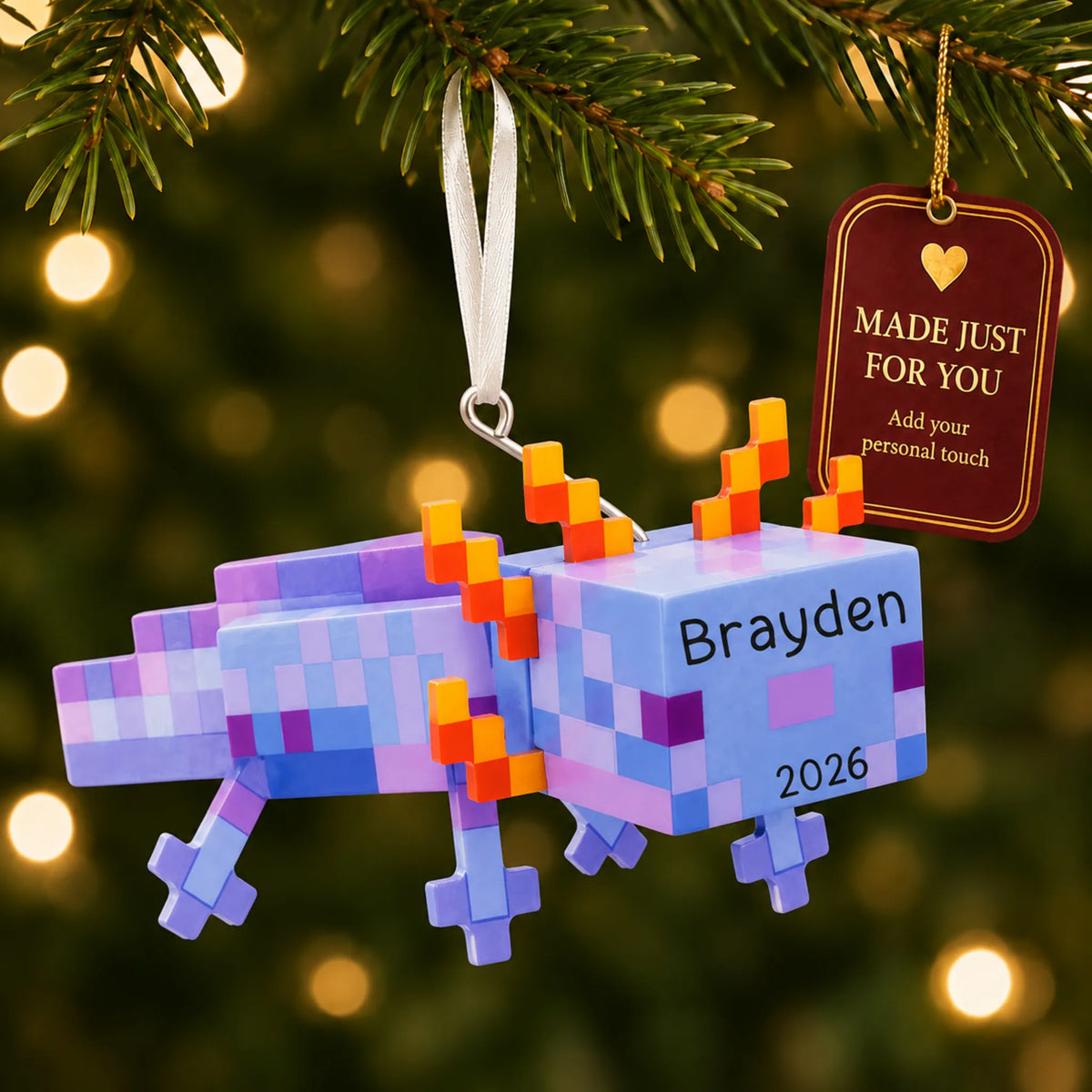 Pixel video game axolotl christmas ornament hanging on a lit Christmas tree with a Made Just For You gift tag