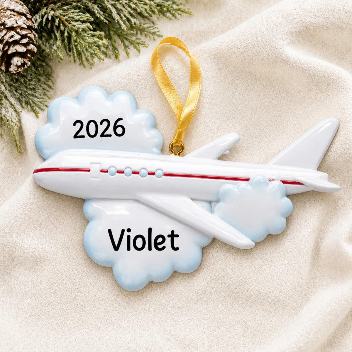Personalized flying airplane travel christmas ornament laid on a soft white knit blanket