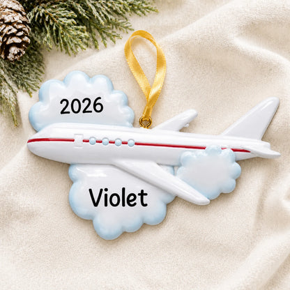 Personalized flying airplane travel christmas ornament laid on a soft white knit blanket