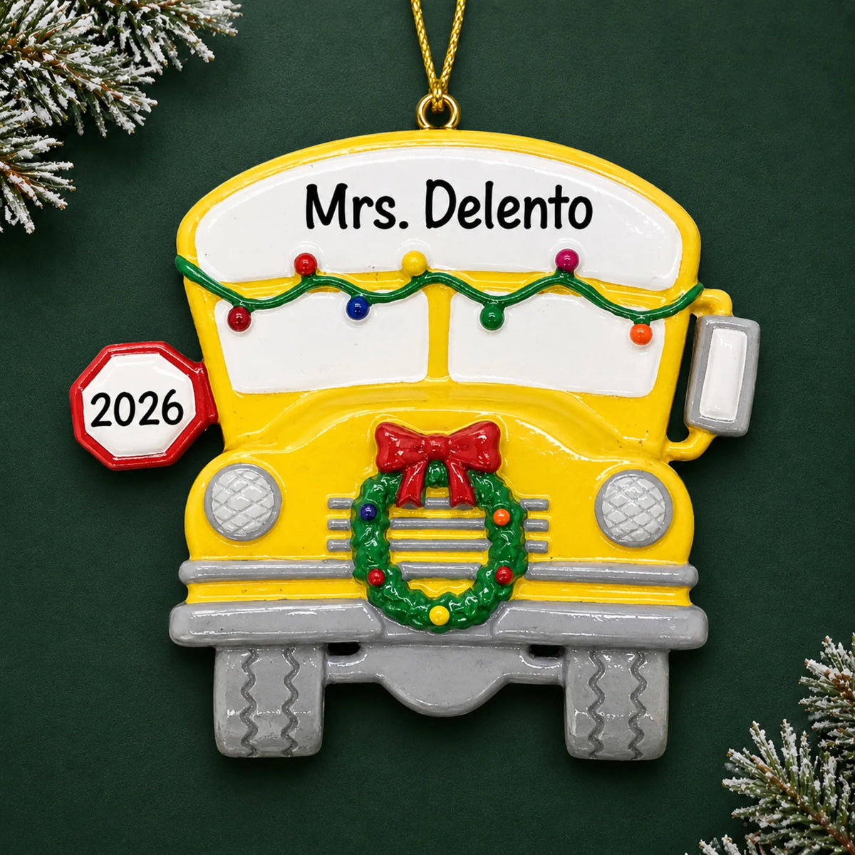 Personalized school bus Christmas ornament with name and year, shown on a green holiday background