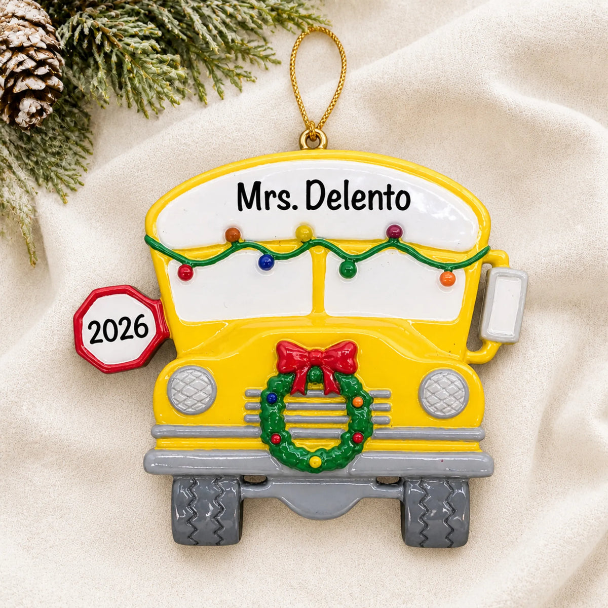 Personalized school bus Christmas ornament shown on a soft white blanket