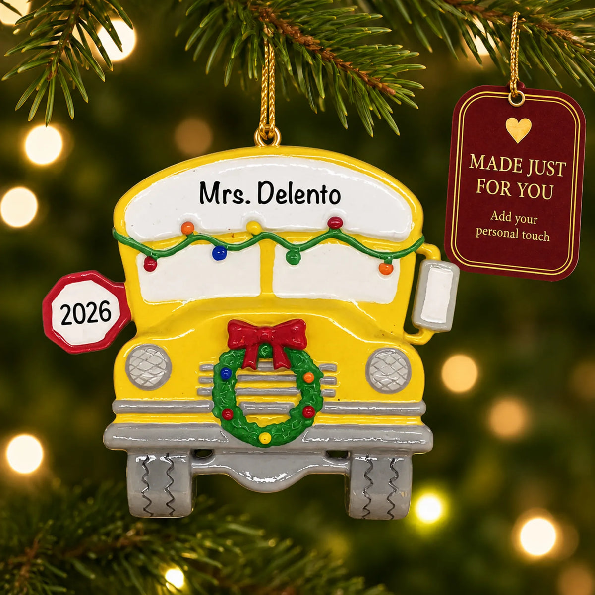 Personalized school bus Christmas ornament hanging among tree lights with a Made Just For You tag