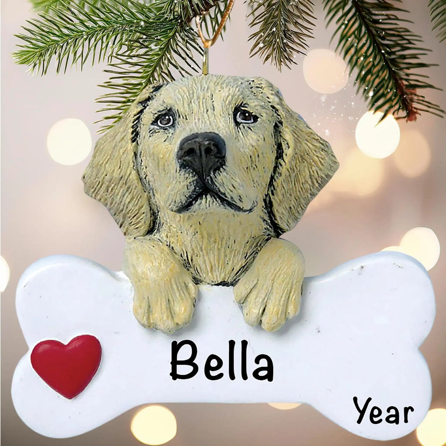 Dog ornament with 'Bella' and 'Year' on a bone-shaped tag, hanging from a Christmas tree.