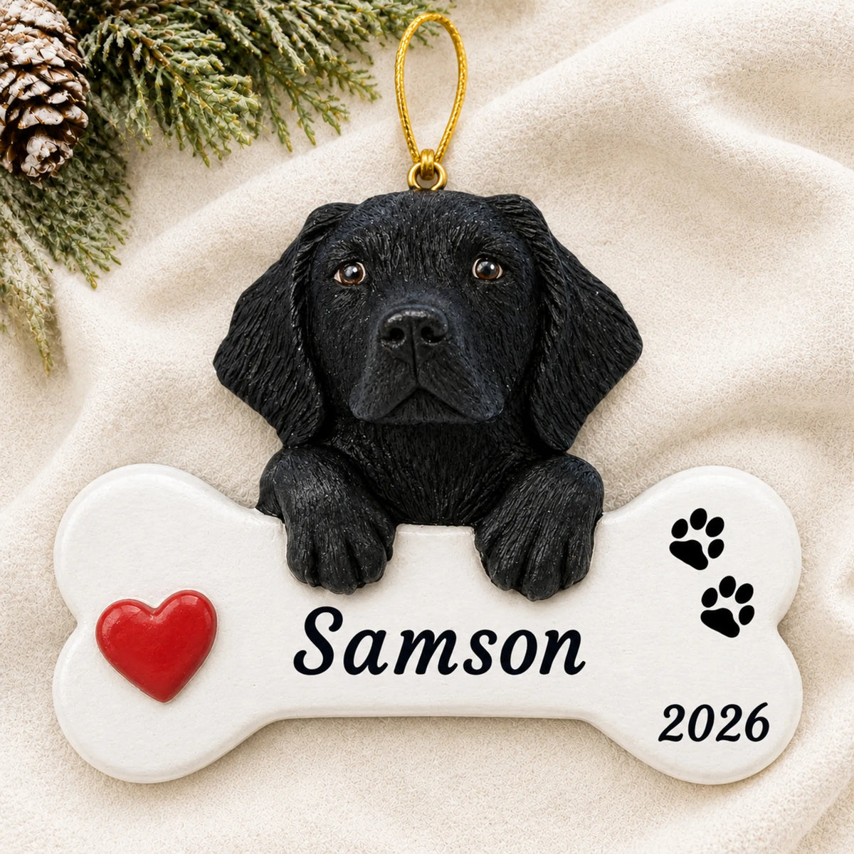 Personalized Black Lab Dog Bone christmas ornament laid on a soft white knit blanket