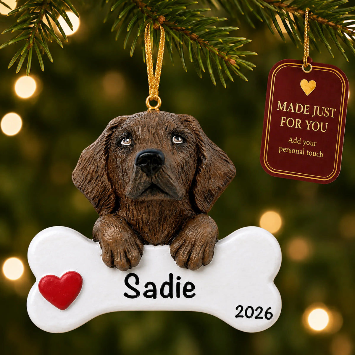 Personalized chocolate Lab Christmas ornament hanging on a lit tree beside a Made Just For You tag