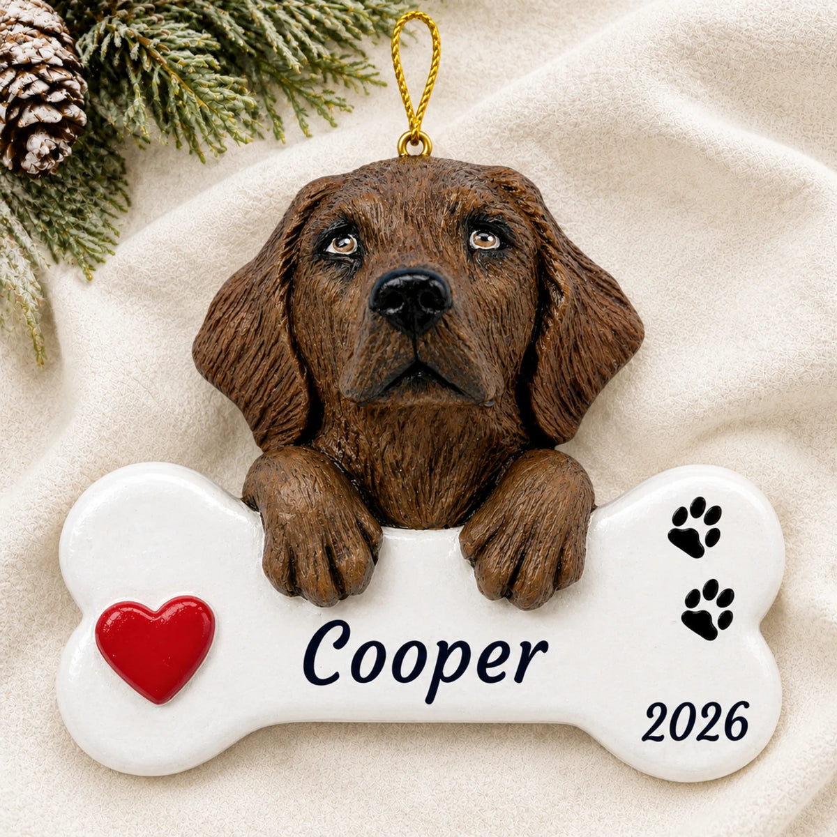 Personalized Chocolate Lab Dog Bone christmas ornament laid on a soft white knit blanket