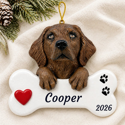 Personalized Chocolate Lab Dog Bone christmas ornament laid on a soft white knit blanket