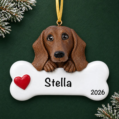 Personalized dachshund dog bone Christmas ornament, engraved with a name and year, on a green holiday backdrop