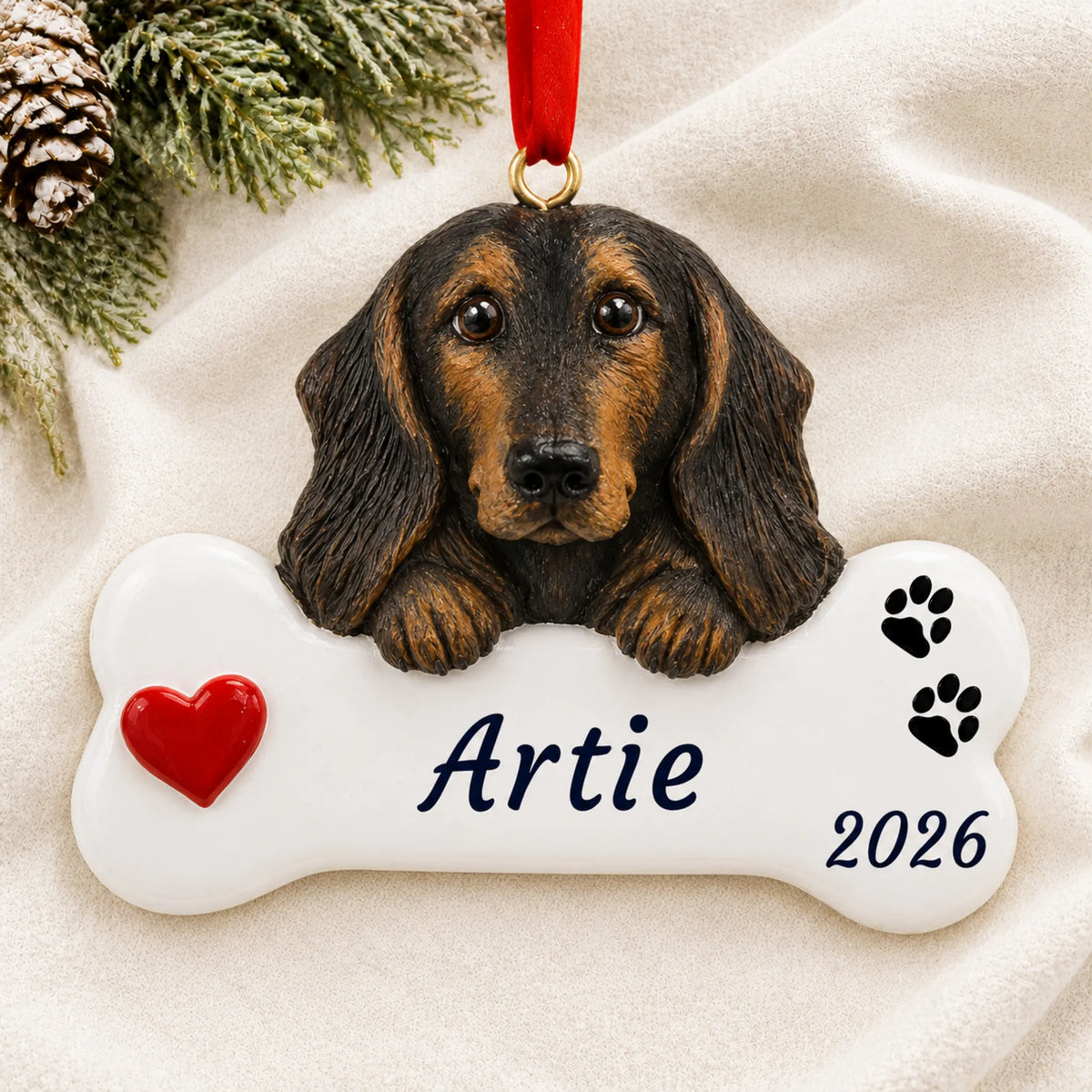 Personalized Black & Tan Dachshund Dog Bone christmas ornament laid on a soft white knit blanket